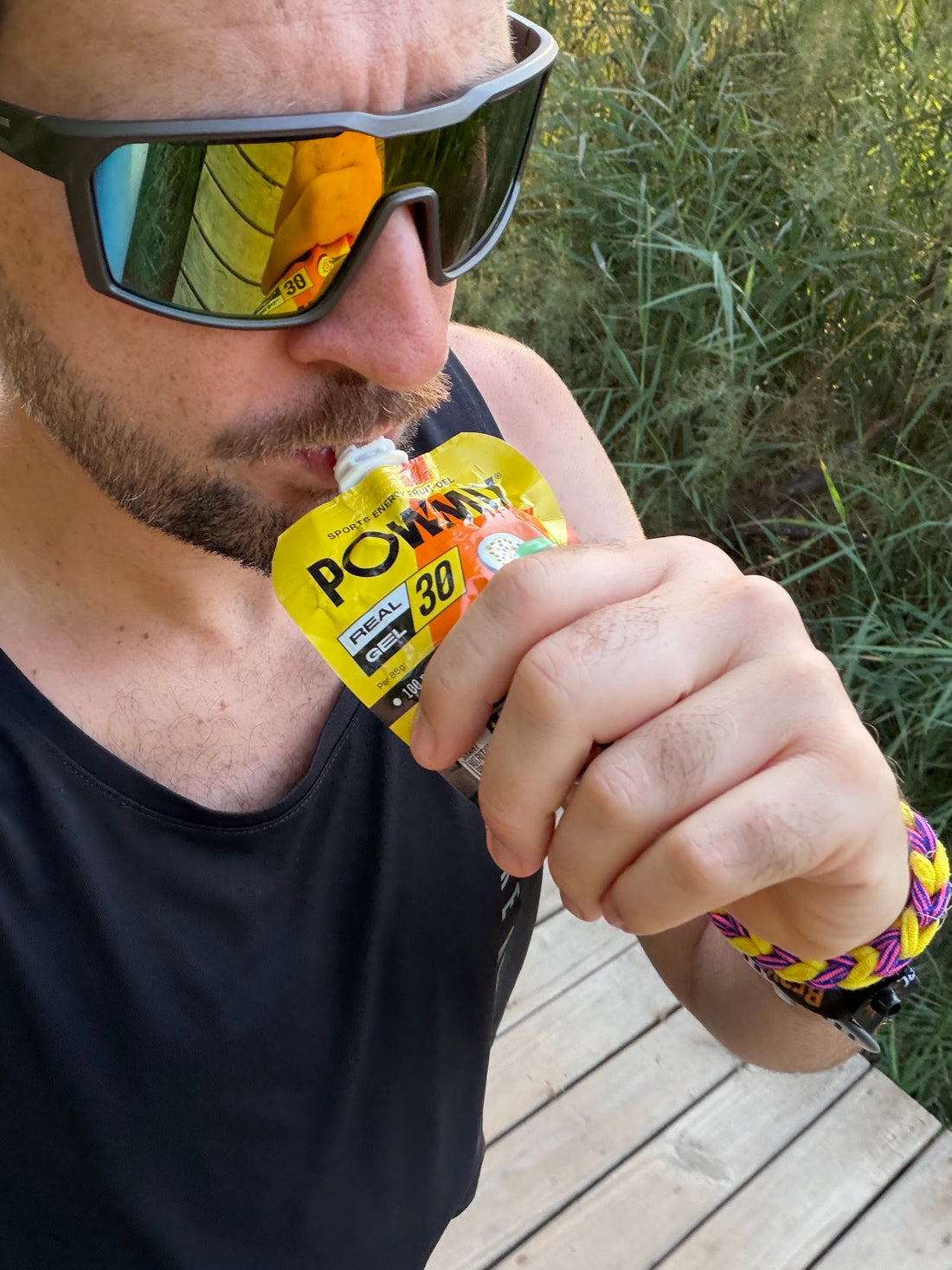 Corredor con gafas de sol tomando un gel POWMIX