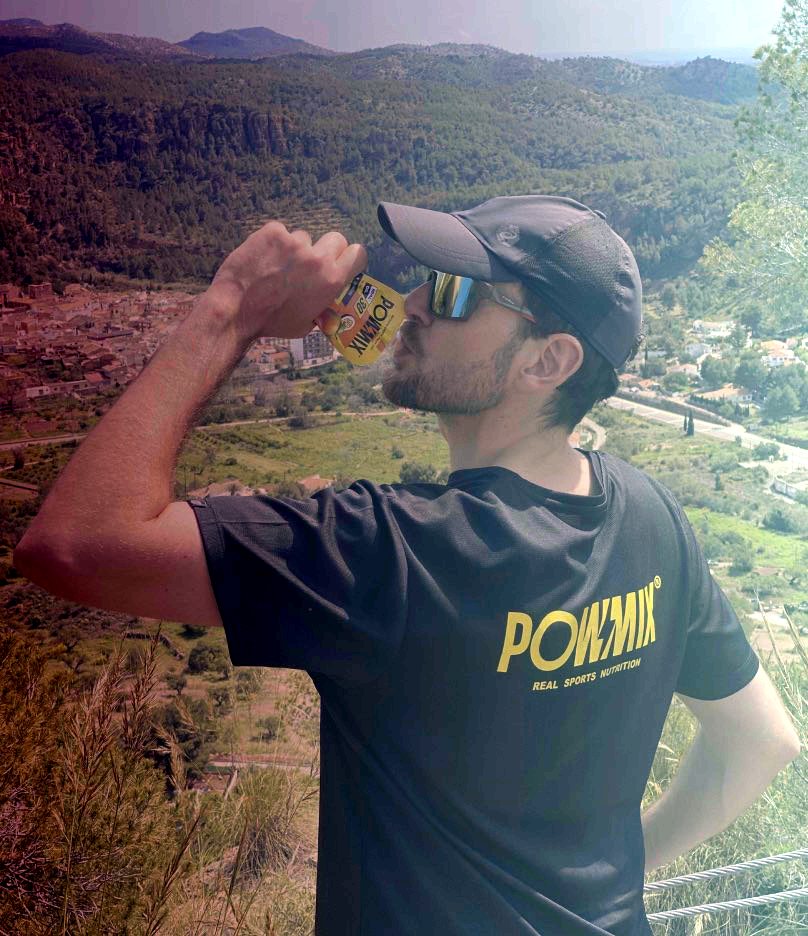 Corredor tomando un gel POWMIX en la montaña