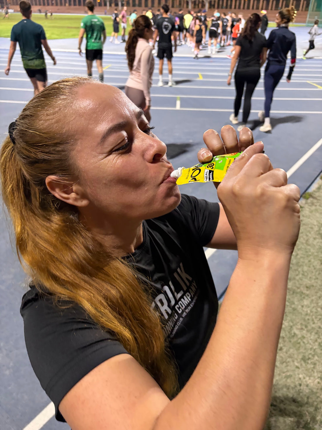 Corredora tomando un gel POWMIX en la pista